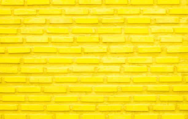 istock Brick wall painted with yellow paint pastel bright tone texture background. Brickwork and stonework flooring interior with rock old pattern clean grid concrete uneven bricks design backdrop. 1482305241
