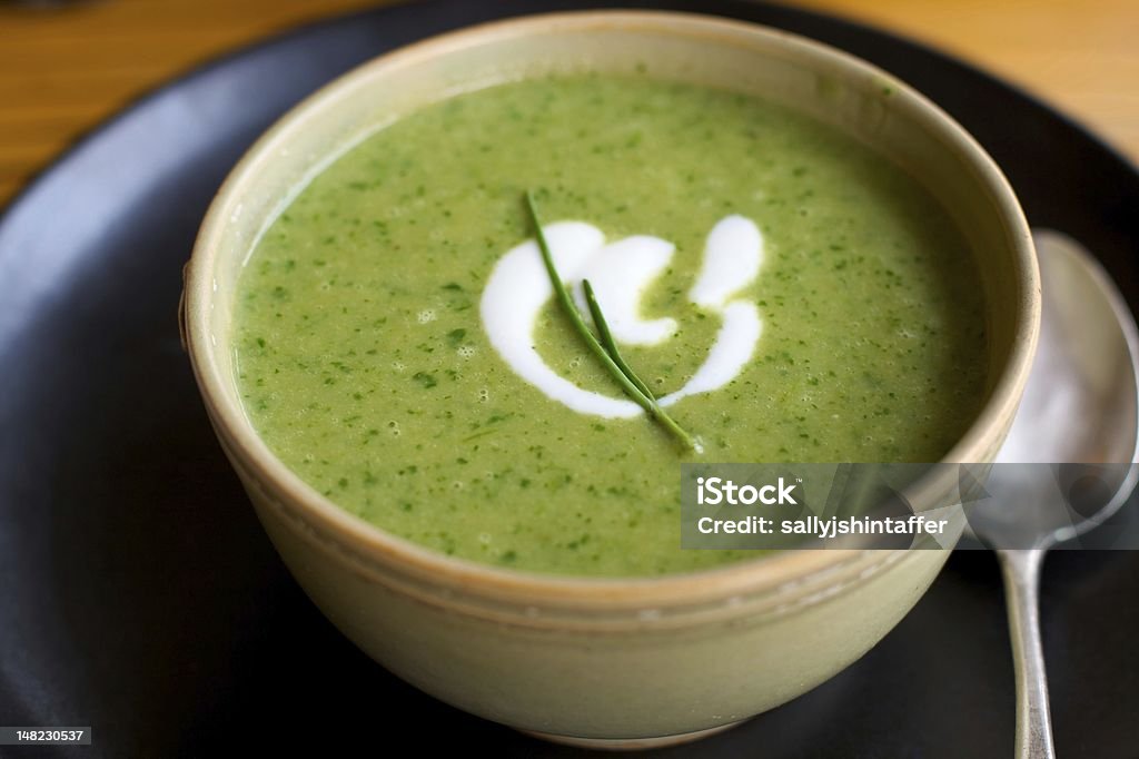 Bright green herb soup Bright green herb soup in a ceramic bowl on a dark plate with a silver spoon. Sorrel Stock Photo