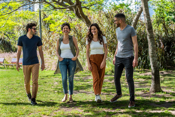 istock Four friends talking and laughing while walking in a public park. 1482307091