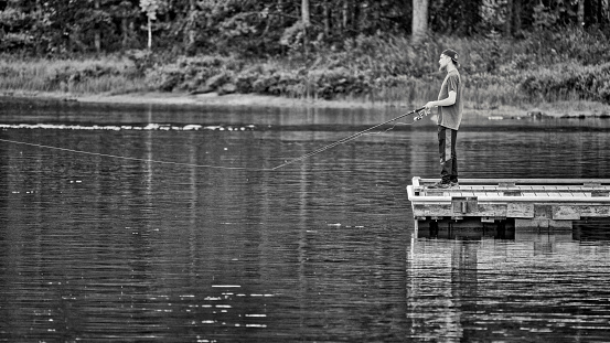 Jasper National Park in Alberta Canada on August  22, 2022:  Young man fishing off a pier on Maligne Lake located in Jasper National Park, Alberta Canada