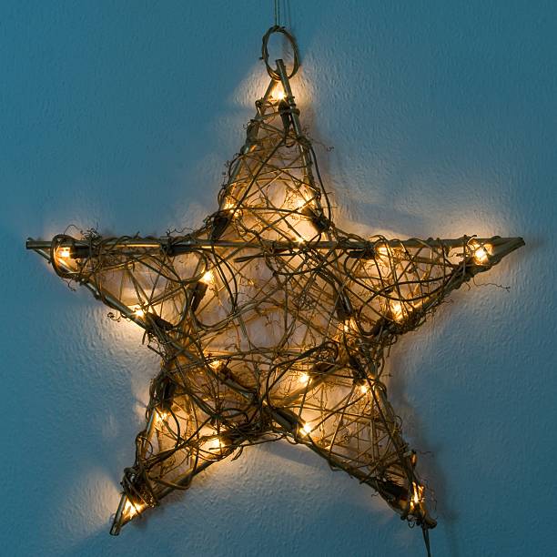 Illuminated Christmas Star An illuminated Christmas Star made of wood is hanging on a wall christmas star shape christmas lights blue stock pictures, royalty-free photos & images