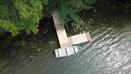 An aerial drone shot of a rowboat at a dock on a lake.