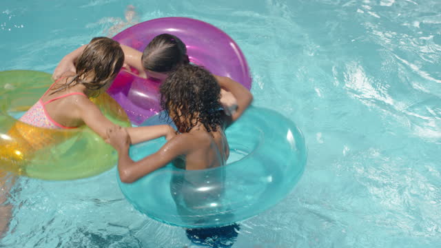 happy children swimming in pool with colorful swim tube inflatable toys kids splashing playfully having fun together on water floats enjoying summer vacation