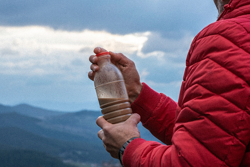Beverage in bottle in front of mountains background.