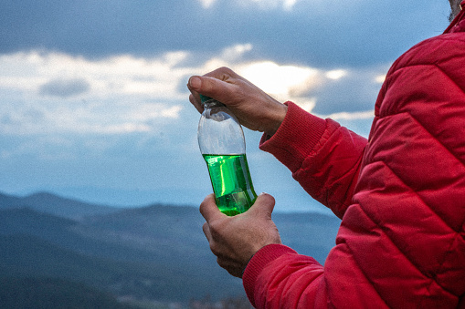 Beverage in bottle in front of mountains background.