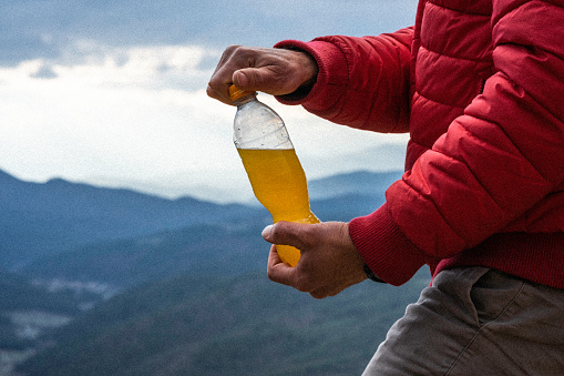 Beverage in bottle in front of mountains background.