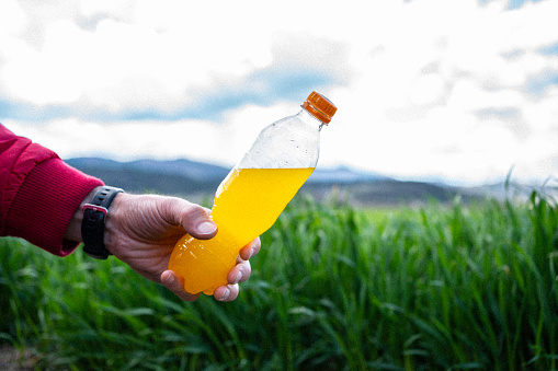 Beverage in bottle on green field background.