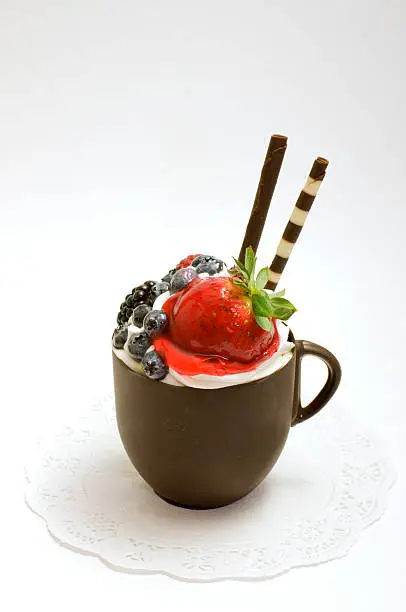 A chocolate cup filled with vanilla mousse and topped with berries makes a decadent and delicious dessert suitable for a special occasion.