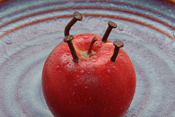 Rusted Nails in Apple Rusted nails in wet apple on wet plate. rusty nails stock pictures, royalty-free photos & images