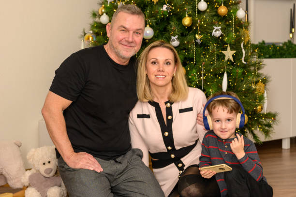 Father and mother sitting together with their five-year-old son in front of the decorated Christmas tree
