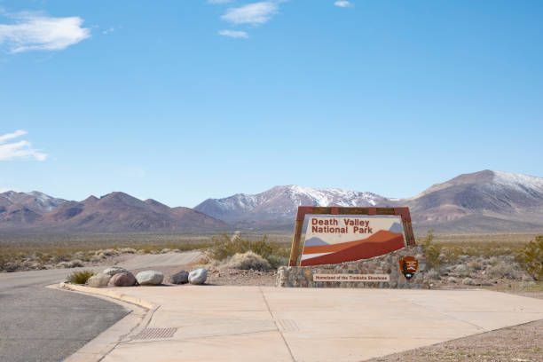 Death Valley, California, USA- March 2023: Sign at the entrance of  Death Valley National Park, in Mojave desert, California USA. with view of road and mountains