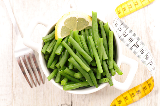 diet food concept- healthy lifestyle or eating- green bean with meter tape