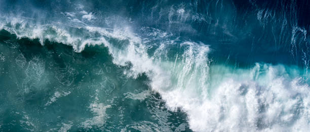 istock Sight from above as a big breaking wave crashes into the blue waters below with its power and strength visible through the white spray and foam, making it a awe moment captured in this panoramic view. 1482335565
