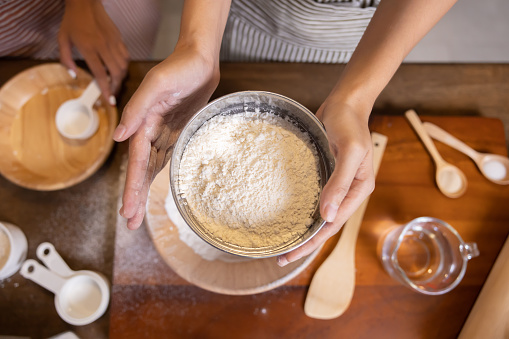 Top View of Woman Hand Sifting Bread Flour Before the Process of Kneading Dough