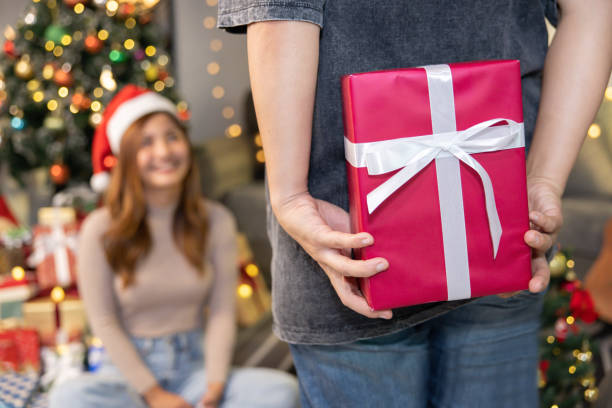 istock a Man Hiding a Christmas Present Behide to Surprise his Girlfriend 1482337134