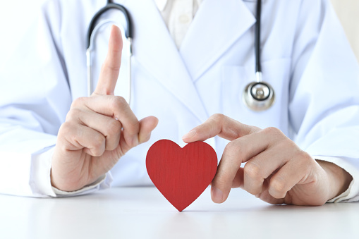 Doctor putting up index finger and red heart object