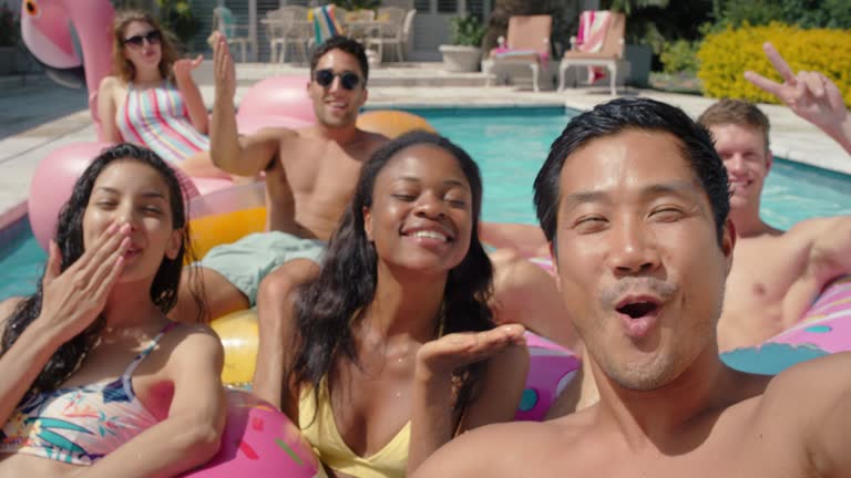 friends in swimming pool young asian man taking video using smartphone sharing summer vacation on social media happy people enjoying summer day outdoors 4k