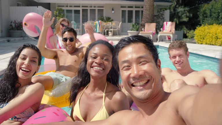 friends in swimming pool young asian man taking video using smartphone sharing summer vacation on social media happy people enjoying summer day outdoors 4k