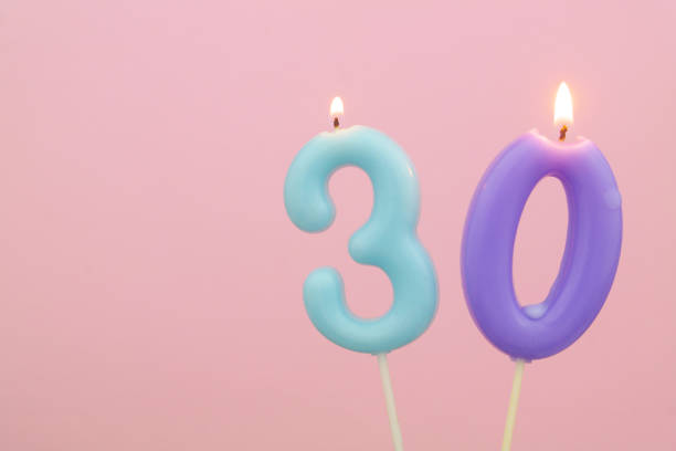 Colorful birthday candle melting on pink background with space for text. Number 30. stock photo