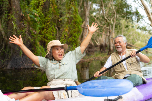 coppia senior asiatica in kayak nel lago insieme. - canoeing canoe senior adult couple foto e immagini stock