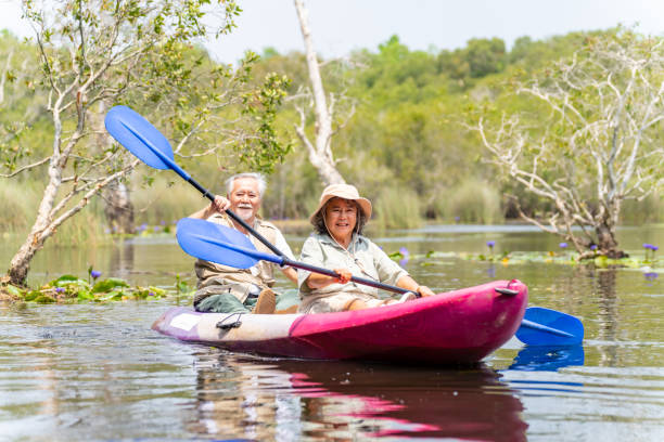 coppia senior asiatica in kayak nel lago insieme. - canoeing canoe senior adult couple foto e immagini stock