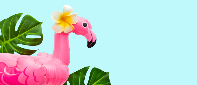 Pink flamingo, tropical leaf monstera and orchid flowers on light background. Summer beach party concept. Flat lay, copy space.