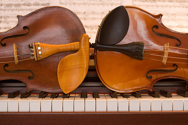 Dois violins deitado em um teclado de piano - foto de acervo