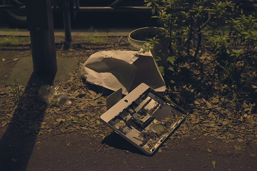 Suginami City, Tokyo, JAPAN - May 13th, 2020: Behold the contrast between the modern and the forgotten in this intriguing urban night scene captured in Suginami City, Tokyo. A discarded Apple iMac computer lies abandoned on the ground amidst a pile of garbage, creating a unique juxtaposition of past and present feelings.