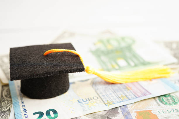 istock Graduation gap hat on Euro and US dollar banknotes money, Education study fee learning teach concept. 1482359684