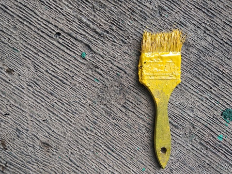close-up yellow paint brush on concrete floor with copy space