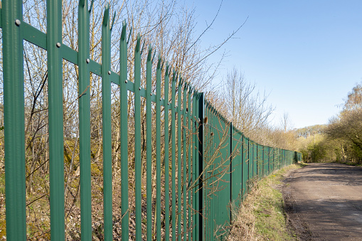 green Palisade security Fencing against a bright blue sky