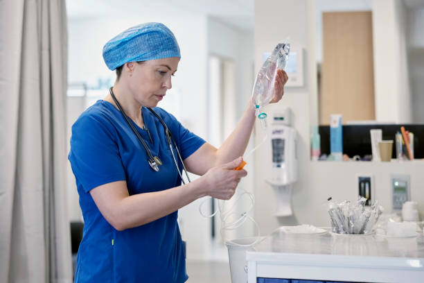 ärztin bereitet einen infusionstropfen für patienten in der notaufnahme vor - durchgezogen stock-fotos und bilder