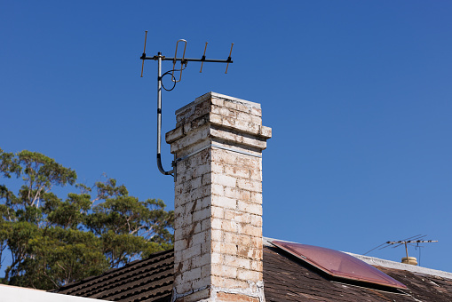 Chimney and antenna against a clear blue sky.
