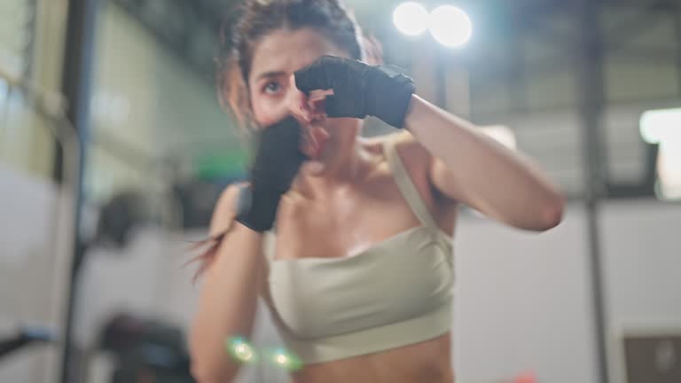 Young Woman With Gloves doing exercise boxing and body bending In A Gym