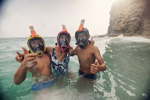 Three kids snorkeling in the sea. The kids are wearing modern full-face snorkel masks. Sunny summer day.\nCanon R5