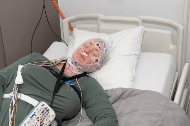 Middle-aged woman measuring brain waves, examining polysomnography in sleep lab Middle-aged woman measuring brain waves, looking polysomnography in a sleep laboratory, High-quality photo Polysomnogram stock pictures, air pressure, sleeping pills, untreated sleep apnea, laser sessions, sleep medicine, oral device, royalty-free photos & images.