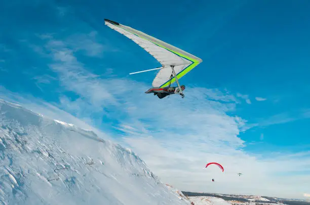 Hang glider pilot launches from the snow cliff. Extreme airborne sport