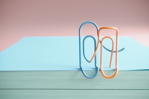 Huggling two paper clips on note pad, symbolizing love concept. (3d render)