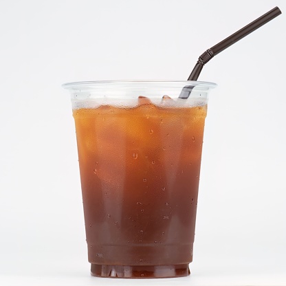 A plastic cup of iced tea beverage with a straw isolated on a white background