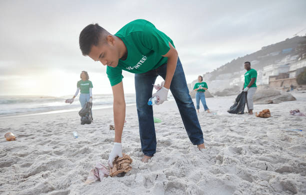 istock Teamwork, cleaning and recycling with man on beach for sustainability, environment and eco friendly. Climate change, earth day and nature with volunteer for community service, pollution and plastic 1482392554