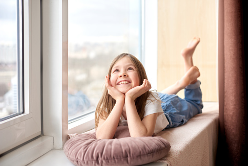 cheerful smiling girl lies and dream on windowsill on vacation