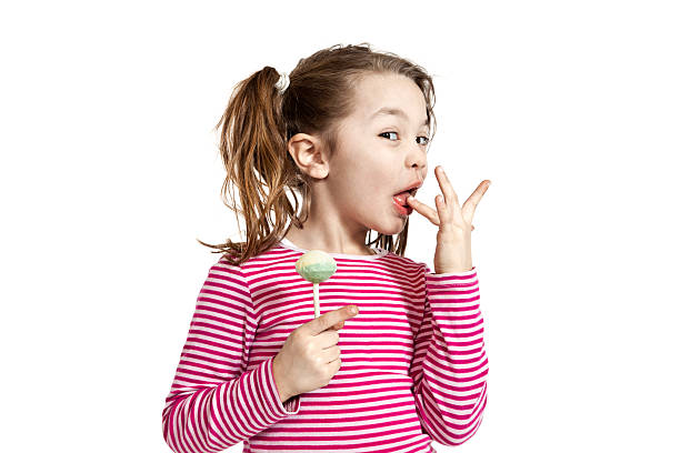 маленькая девочка с леденец на палочке - finger in mouth стоковые фото и изображения