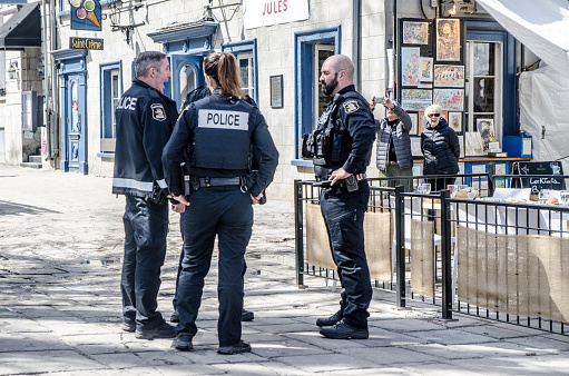 Four police officers discussing downtown Quebec during springtime day