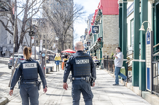 Two police officers walking downtown Quebec during springtime day