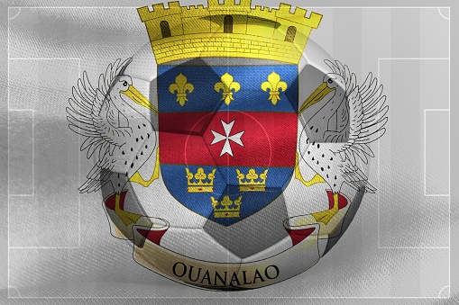 A photo of a waving Saint Barthelemy(St Barts) flag with a football ball-shaped outline in the center