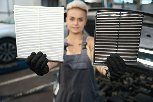 Close up view of female employees hands in gloves showing cabin air filters in automobile repair service