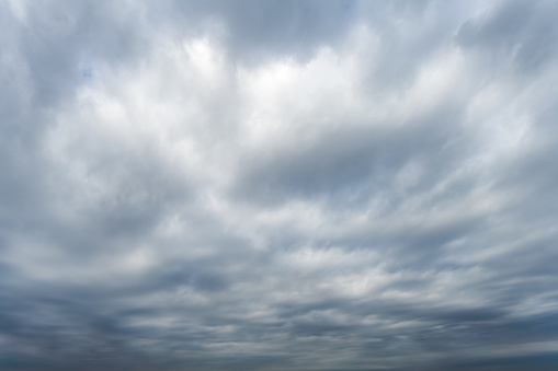 Section of the sky with cumulus and rain clouds over the tree tops on a horizon