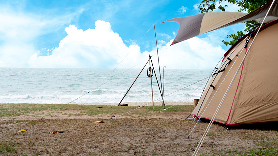 Visible only half of brown tent. Holidays on the sandy beach. Surf the colorful sea under the blue sky.