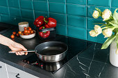 woman prepare dinner on electrical hob at home kitchen, closeup