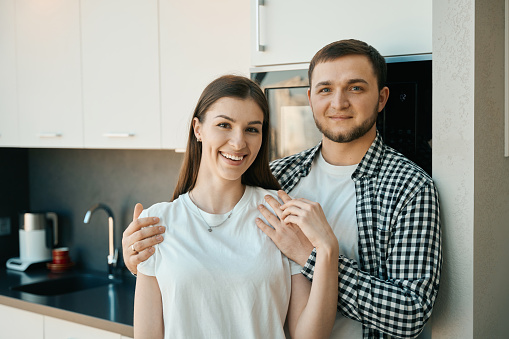Bearded man gently hugs his wife by the shoulders, guys in comfortable home clothes